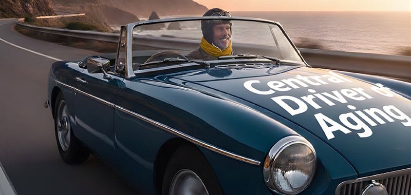 Man driving a vintage convertible along a coastal highway at sunset with the words “Central Driver of Aging,” illustrating the role of chronic inflammation in age-related decline.